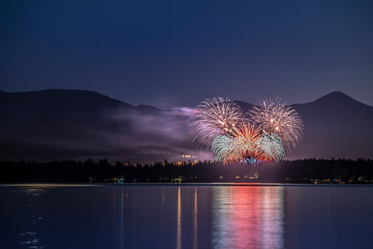 Fireworks of celebration and festival in the mountains on the ocean with water reflections at night