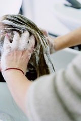 A vertical closeup shot of a hairdresser washing a woman's long hair in a beauty salon