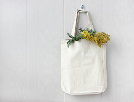 white eco bag and Mimosa branch on a light background.