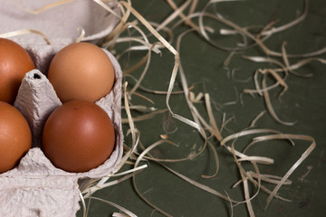 Fresh brown eggs in a special cardboard box (egg tray) decorated with hay. Egg storage concept, preparing for Easter, place for text