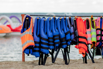 Close-up group of Life jackets or life vests hanging on the wall of the boating station against sea coast