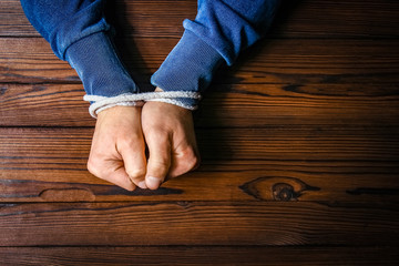 hands with a rope on a wooden background