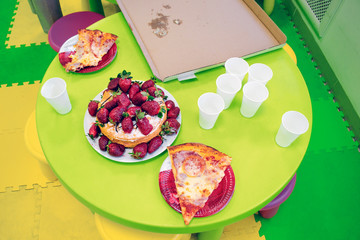 festive strawberry cake and pizza with plastic white cups on the table