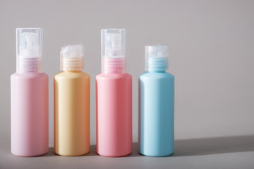 Travel kit. Set of four plastic bottles for cosmetic products. Gray background with shadows.