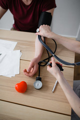 Red-haired doctor measures pressure to a sick patient with signs of coronavirus