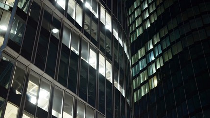 Fototapeta na wymiar Pattern of office buildings windows illuminated at night. Lighting with Glass architecture facade design with reflection in urban city.
