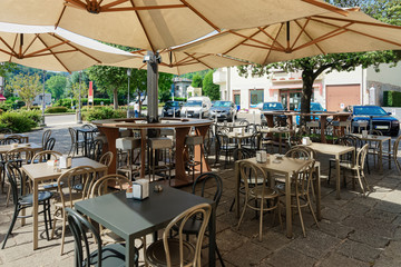 Street restaurant with tables and chairs under umbrellas at hotel in Italy
