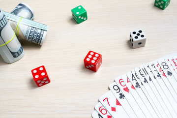 money dollars dice playing cards gambling on a light wooden table