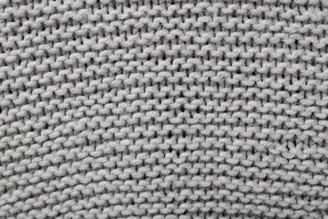 Texture of gray woolen knitted sweater closeup. Abstract textured background for wallpaper.