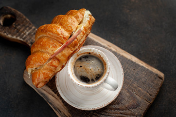 coffee and croissant with sausage, cheese and salad on a stone background. Breakfast concept