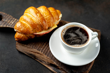 coffee and croissant with sausage, cheese and salad on a stone background. Breakfast concept
