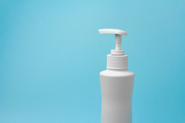 Mock up of white bottle with a dispenser on a blue background. Copy space for advertisement for cosmetic product.