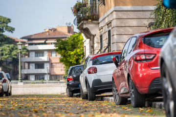 Modern cars parked on city street side in residential discrict. Shiny vehicles parked by the curb. Urban transportation infrastructure concept.