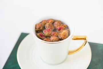 Herbal tea dried roses in cup.Hot healthy drink on the open books.White background.Minimalist style.