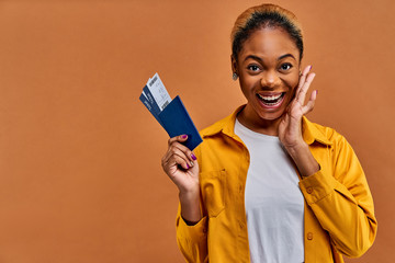 Joyful girl in a yellow suit holds a passport with tickets in hand. Travel concept