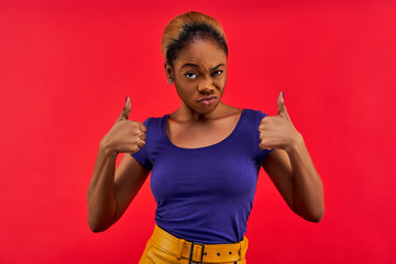 Proud woman in earrings in a blue T-shirt in a yellow skirt shows like gesture. Emotions concept