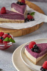 raw vegan double-layer cake with black currant on a light gray background under a concrete texture. Healthy eating, delicious dessert without baking