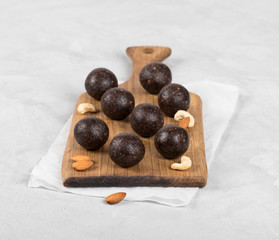 Energy candies from dried prunes, dates, dried apricots and almonds, cashews, walnuts on a wooden Board on a light background