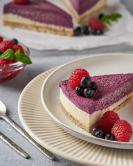 raw vegan double-layer cake with black currant on a light gray background under a concrete texture. Healthy eating, delicious dessert without baking