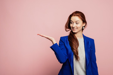 Woman showing pointing on pink background. Very fresh and energetic beautiful young girl smiling happy presenting on pink background