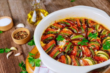 Stewed vegetable ratatouille with mozzarella cheese in white oven pan.