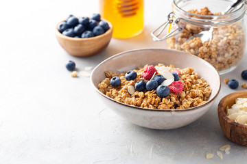 Breakfast. Muesli with blueberries, raspberries, almonds and honey on a light background. Space for text.