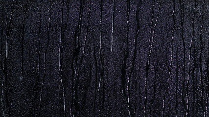 Droplets of water on black glass background running down.