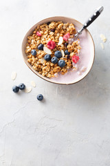 Breakfast. Cereal muesli with yogurt, blueberries, raspberries, almonds and honey on a light background. Space for text. Top view.