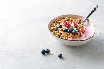 Breakfast. Cereal muesli with yogurt, blueberries, raspberries, almonds and honey on a light background. Space for text.