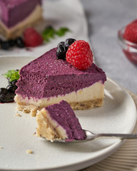 raw vegan double-layer cake with black currant on a light gray background under a concrete texture. Healthy eating, delicious dessert without baking