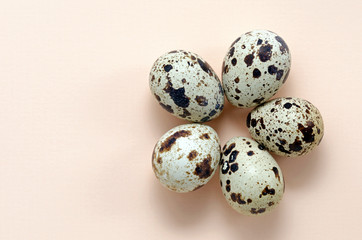 Obraz premium quail eggs laid out in the form of a flower on a pink peach background top view. Easter holiday eggs. The concept of spring, warmth, flowering, love, relationships. universal greetings.