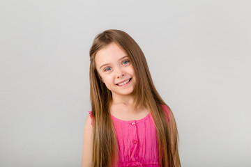 portrait of a little girl with long hair in pink clothes on a white background. happy baby girl smiling on white background isolate