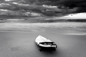 Black and white photo of a surfboard on the beach, Sydney Australia