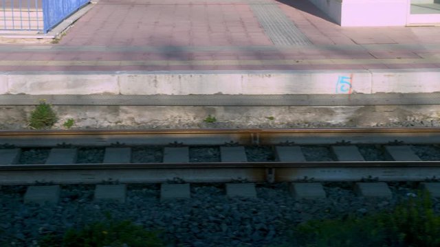 View through the window of departuring train, public vehicle accelerating speed, metal line of rails. Train moving with high speed in countryside, steel railroad motion 