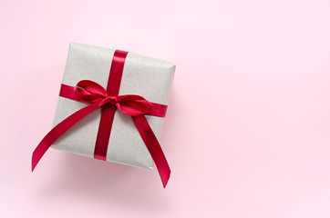 gift wrapped in paper from environmentally friendly paper from recycled waste with red satin ribbon...