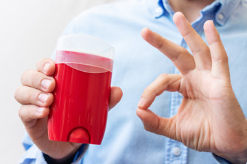 Man shows deodorant and sign okay with fingers, man's hands, cropped image, close-up, copy space