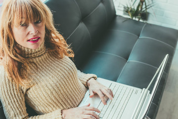 adult woman with laptop in the living room of house or apartment