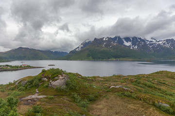 A mystical fjord in Norway with mountains and fog hanging over the water in polar day. midnight sun, selective focus