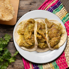 Mexican pork chicharron with green sauce tacos on wooden background