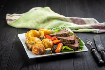 beef roasted in fresh herbs surrounded by baked vegetables