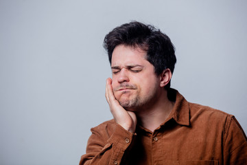 Fototapeta premium guy in a shirt with a toothache on a gray background