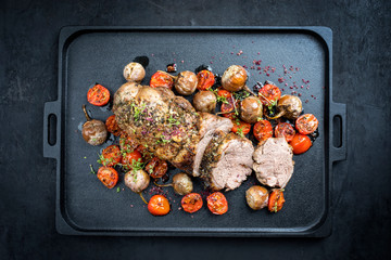 Traditional barbecue rolled lamb roast sliced with tomatoes and mini eggplant as top view on a...