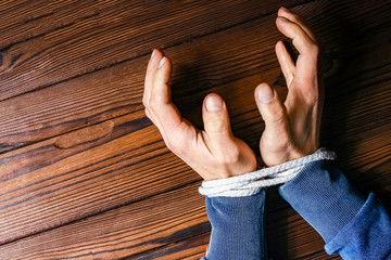 hands with a rope on a wooden background