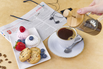 coffee cup with a gold border on olive wood board. Breakfast setting, coffee oatmeal cookies with raspberries and mini tosca cake