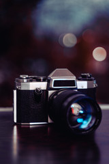 Fototapeta na wymiar Old film camera with a telephoto lens against blurry background