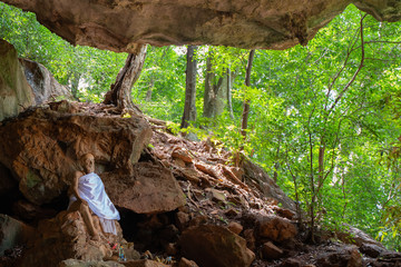 Shrouded Buddhist Thai rock monk sculpture surrounded by Forest (Wat Suwan Kuha)