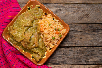 Mexican pork chicharron with green sauce and rice on wooden background