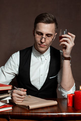 man writer, scientist with glasses at the table with books