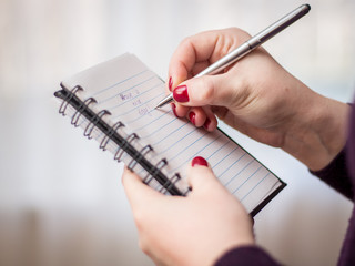 A woman is writing notes in the notebook close up
