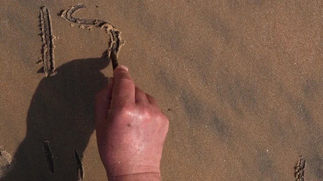 Male hand writes Israel on the sea sand